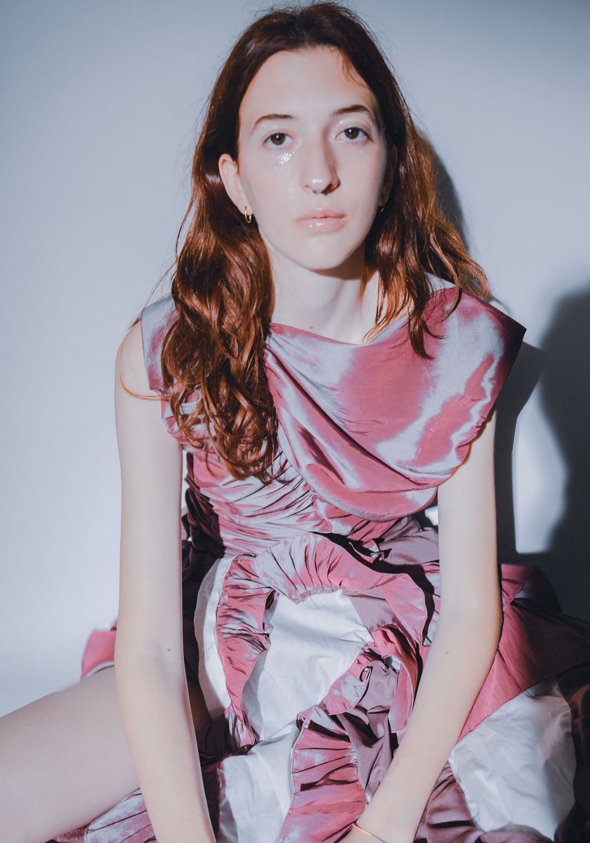 Model in a pink and silver ruched dress, sitting