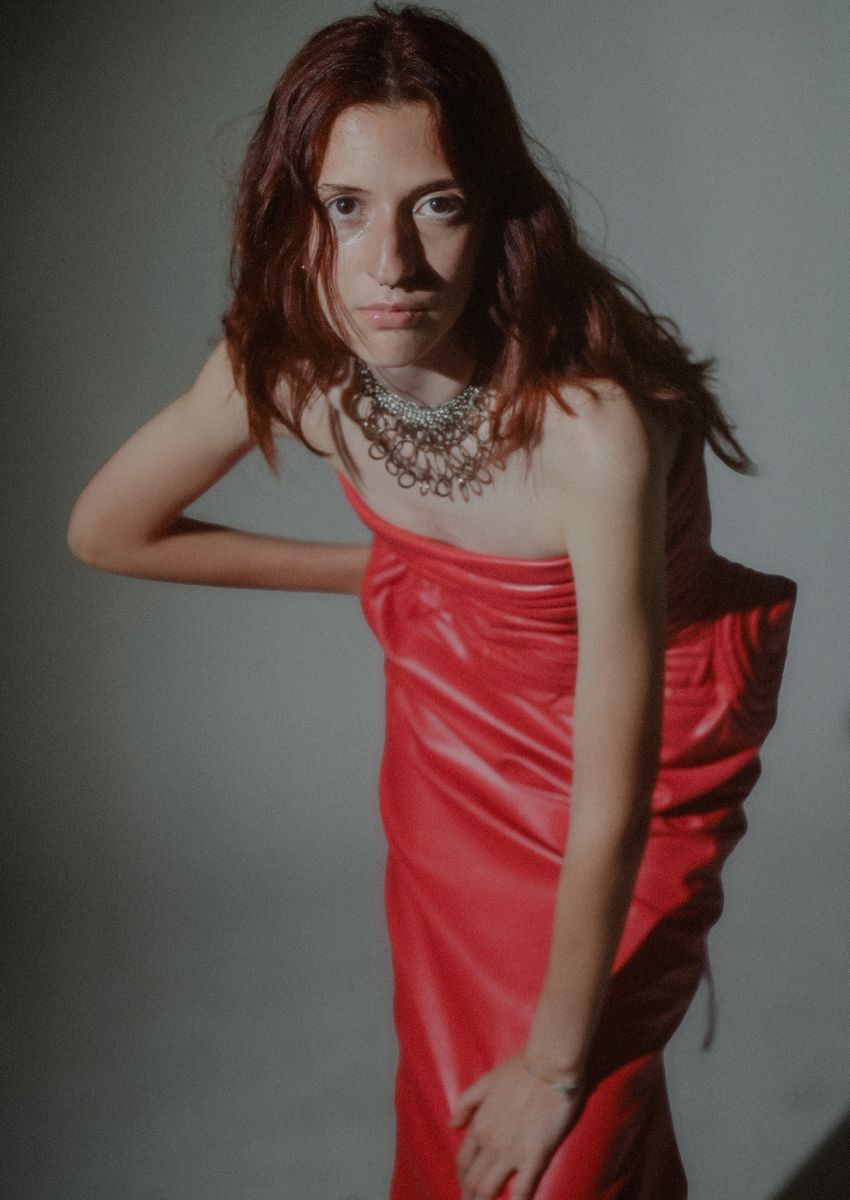 Model in a red dress leaning back in profile